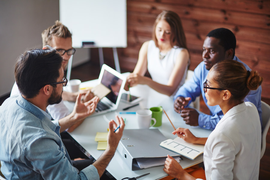 Diverse business professionals discussing ideas and collaborating during a team meeting in a modern office setting