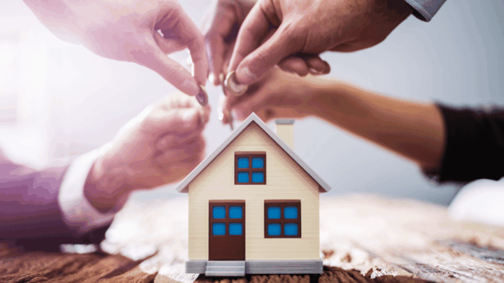 A symbolic real estate investment scene featuring multiple hands placing coins above a miniature house, representing how to identify institutional-grade syndication deals in Albany NY. The image highlights collaborative investing, real estate syndication partnerships, passive investor participation, multifamily property acquisition, capital pooling, institutional-level investment opportunities, wealth-building strategies, and evaluating high-quality real estate deals for long-term returns.
