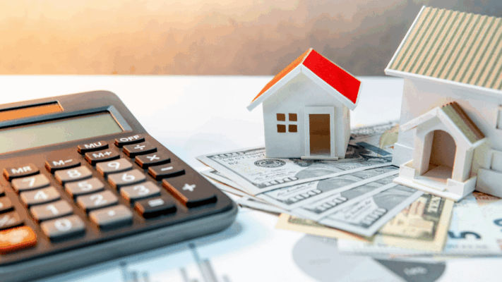 Calculator, model houses, and cash on financial documents representing passive real estate investing and property investment planning 