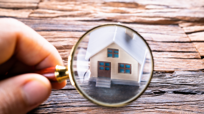 A magnifying glass focuses on a miniature house placed on a rustic wooden surface, symbolizing the importance of closely examining a property before making an investment decision. The image is ideal for topics such as **a complete guide to evaluating multifamily investment opportunities**, property due diligence, multifamily market analysis, investment research, property inspections, financial and operational assessment, risk evaluation, acquisition strategy, real estate underwriting, and making informed multifamily investment decisions.
