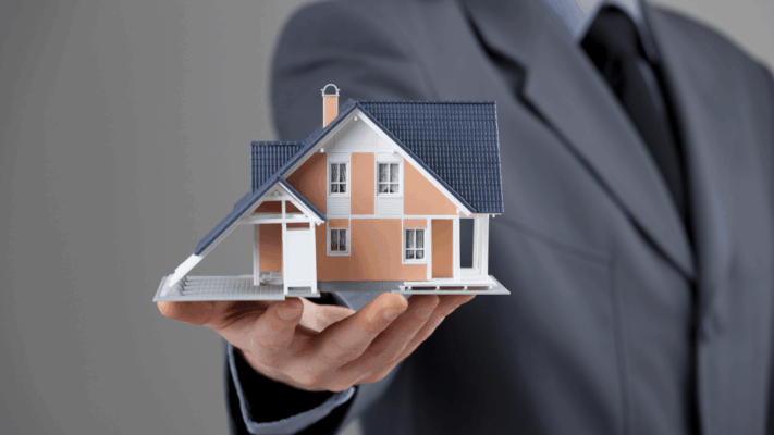 A professional real estate investment concept featuring a businessperson holding a detailed house model, symbolizing advanced portfolio benchmarking for Albany NY investors. The image represents passive real estate investing, portfolio performance analysis, multifamily investment benchmarking, real estate syndication strategies, asset allocation, investment comparison, long-term wealth building, commercial property evaluation, financial performance metrics, and data-driven portfolio optimization for Albany NY real estate investors.