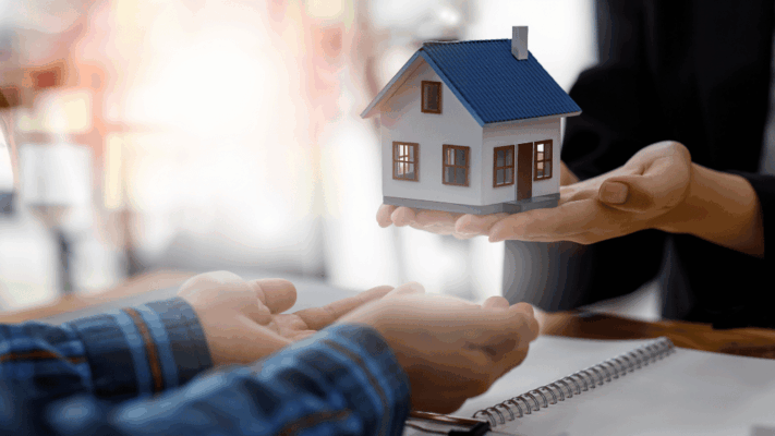A professional real estate consultation scene featuring an advisor presenting a house model to a prospective investor across a table, symbolizing advanced tax efficiency for passive investors in Albany NY. The image represents passive real estate investing, tax-efficient investment strategies, real estate syndication, multifamily property ownership, wealth preservation, long-term financial planning, tax optimization, asset protection, and building generational wealth through commercial real estate investments.