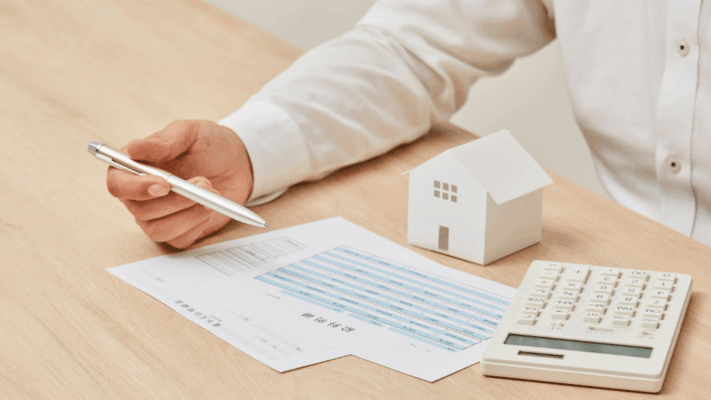 A clean, professional real estate investment scene featuring an investor reviewing financial documents with a calculator, pen, and model home on the table. The image represents the fundamentals of real estate syndication, investment planning, financial analysis, passive real estate investing, due diligence, underwriting, commercial real estate education, beginner-friendly investment guidance, and understanding how multifamily syndications work for new investors in Albany NY.