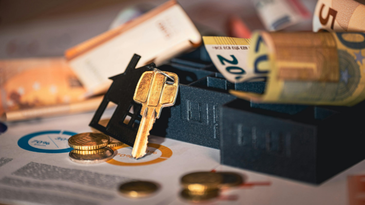 A miniature house with a key rests on top of financial documents alongside cash, coins, and rolled banknotes, symbolizing the wealth-building potential of real estate investing. The image highlights passive income, long-term financial growth, and property ownership, making it ideal for topics such as **building long-term wealth through passive real estate investing**, real estate syndications, passive investing, financial planning, investment returns, cash flow, wealth creation, and portfolio diversification.
