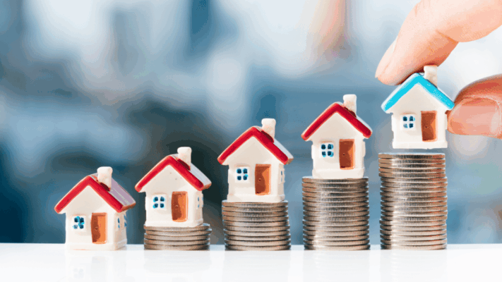 A real estate investment growth concept featuring a series of model homes placed on stacks of coins, illustrating increasing property value and wealth accumulation. A hand positioning the final home symbolizes strategic acquisition and experienced decision-making. The image represents multifamily investment sourcing, value-add acquisitions, commercial real estate opportunities, disciplined underwriting, sponsor expertise, portfolio growth, deal selection, long-term wealth creation, passive investing, and how experienced sponsors consistently source higher-quality investment opportunities.