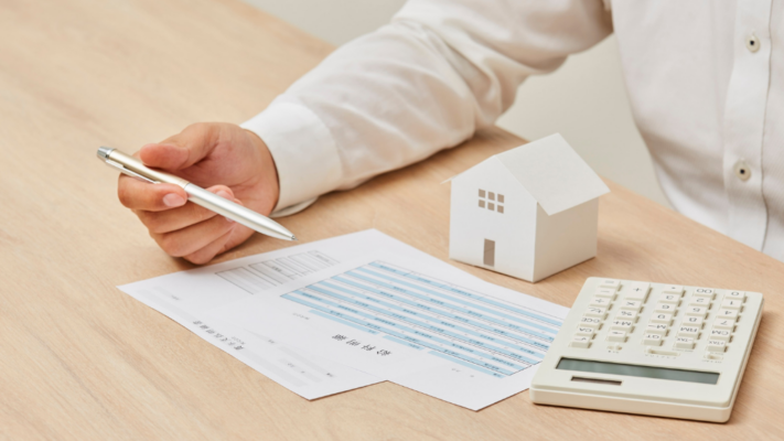 A person reviews a financial statement while holding a pen, with a miniature house model and calculator nearby, representing the process of monitoring real estate investment performance. The clean composition emphasizes tracking financial metrics, reviewing reports, and making informed investment decisions. It is well suited for topics such as **how passive investors can track investment performance**, quarterly investor reports, cash flow monitoring, return on investment (ROI), financial reporting, real estate syndications, multifamily investment performance, portfolio management, distributions, and long-term investment tracking.
