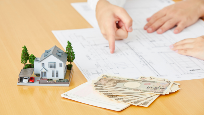 A detailed model home sits beside cash while two people review property plans, with one pointing to the blueprint as they discuss next steps. The image illustrates the active oversight and financial decision-making that takes place after acquiring a multifamily property. It is ideal for topics such as **how sponsors monitor multifamily performance after acquisition**, asset management, business plan execution, capital improvements, budget oversight, operational performance, property management, value-add strategies, investor reporting, financial monitoring, and maximizing long-term multifamily investment returns.
