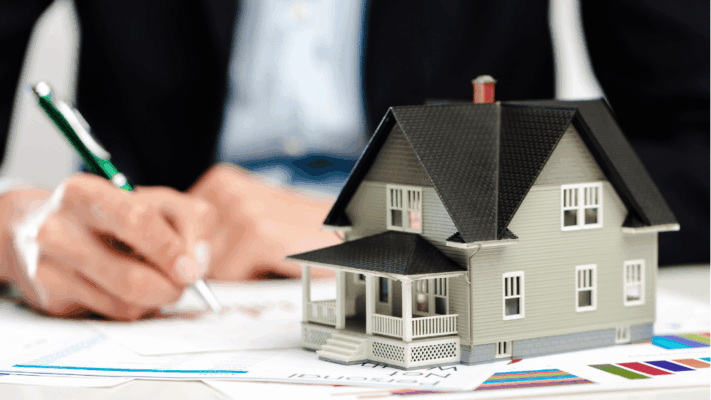 A professional real estate investment scene featuring a model home placed on financial reports while an investor reviews and signs documents in the background. The image represents analyzing a real estate syndication offering memorandum, reviewing investment details, due diligence, underwriting, financial projections, property evaluation, sponsor transparency, multifamily investment research, risk assessment, and understanding the key components of an offering memorandum before making an investment decision.