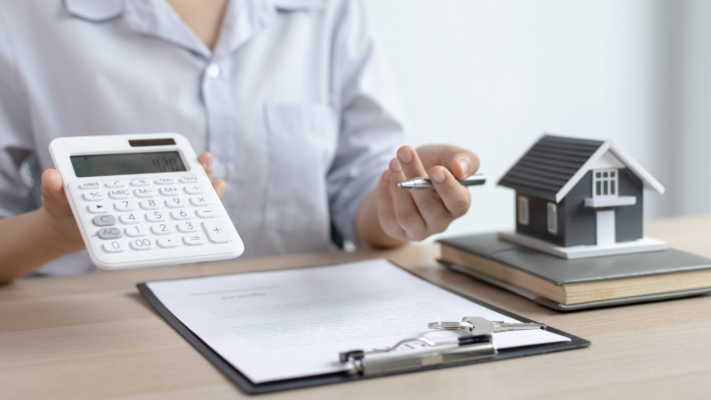 A person holds a calculator and pen while reviewing investment documents, with a model home displayed beside a clipboard, symbolizing the process of analyzing real estate performance and financial results. The image emphasizes reviewing key metrics, interpreting financial data, and measuring investment progress over time. It is ideal for topics such as **understanding quarterly investor reports**, real estate syndications, multifamily investment reporting, financial performance, cash flow analysis, distributions, portfolio updates, asset management, investor communication, and tracking long-term investment performance.

