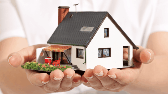 A close-up of a model home held securely in two hands, symbolizing stewardship, protection, and the potential to enhance property value through thoughtful improvements. The image represents value-add multifamily investing, commercial real estate acquisitions, property repositioning, asset management, operational improvements, renovation strategies, passive real estate investing, long-term wealth creation, increased net operating income (NOI), and transforming underperforming properties into higher-value investment assets.